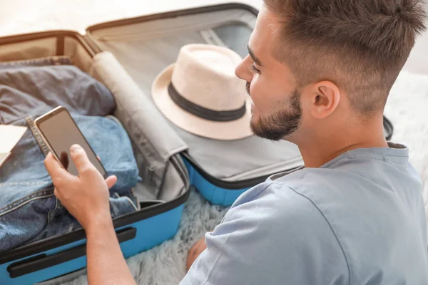 Young man packing luggage at home — Stock Photo, Image