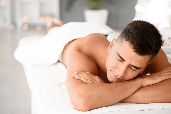 Przystojny mężczyzna poddawany leczeniu kamieniami spa w salonie piękności — Zdjęcie stockowe