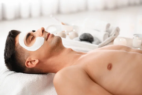 Handsome man with facial mask relaxing in spa salon — Stock Photo, Image