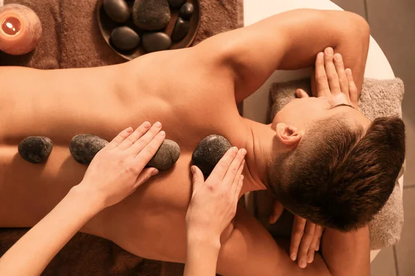 Knappe man ondergaat behandeling met spa stenen in schoonheidssalon, bovenaanzicht — Stockfoto