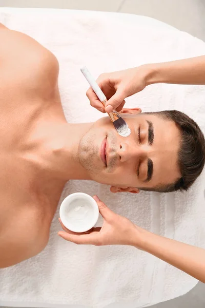 Knappe man ondergaat behandeling met gezichtsmasker in schoonheidssalon — Stockfoto