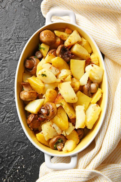 Lezzetli pişmiş mantarlı fırın yemeği ve koyu arkaplanda patates.