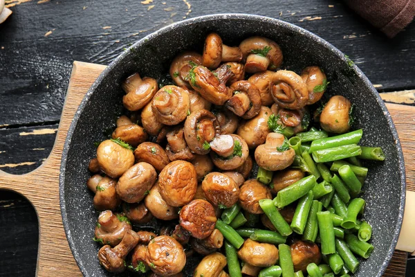 Сковородка с вкусными грибами и зелеными бобами на столе — стоковое фото