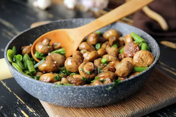 Сковородка с вкусными грибами и зелеными бобами на столе — стоковое фото