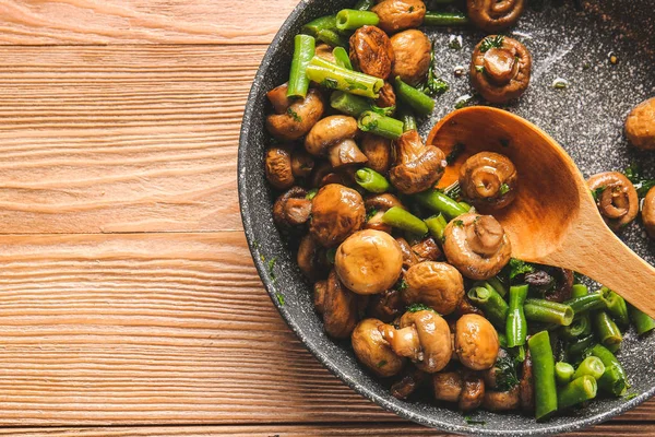 Сковородка с вкусными грибами и зелеными бобами на столе — стоковое фото