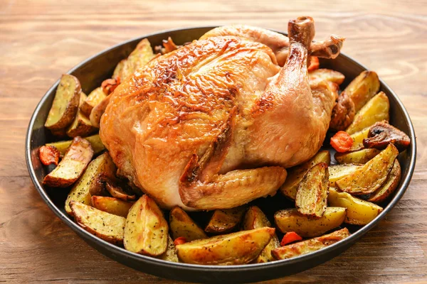 Блюдо с запеченной курицей и картошкой на деревянном столе — стоковое фото