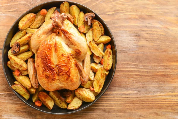 Блюдо с запеченной курицей и картошкой на деревянном столе — стоковое фото