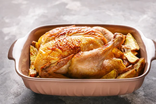 Dish with baked chicken and potato on dark background — Stock Photo, Image