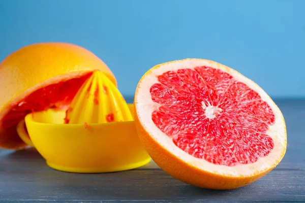 Fresh cut grapefruit and juicer on wooden table — Stock Photo, Image