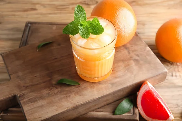 Vaso de zumo y pomelos frescos sobre la mesa — Foto de Stock