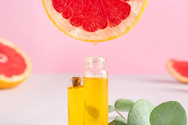 Грейпфрутовое эфирное масло, капающее в бутылку на столе — стоковое фото