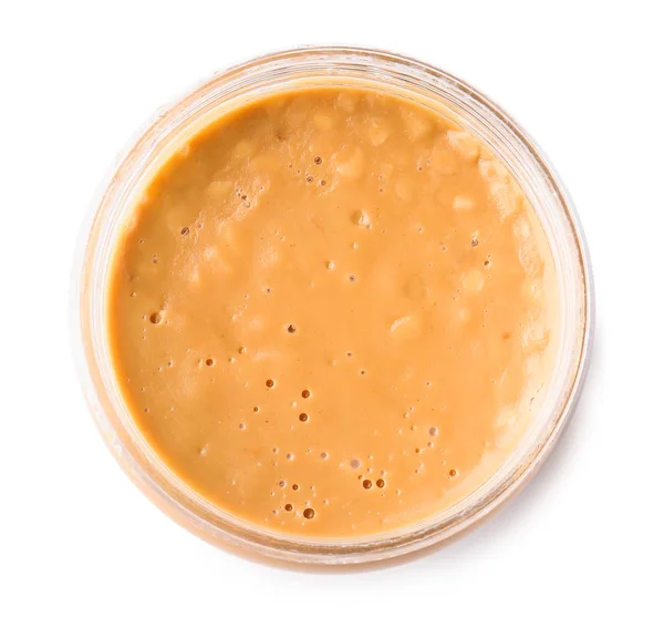 Вкусное арахисовое масло в банке на белом фоне, вид сверху — стоковое фото
