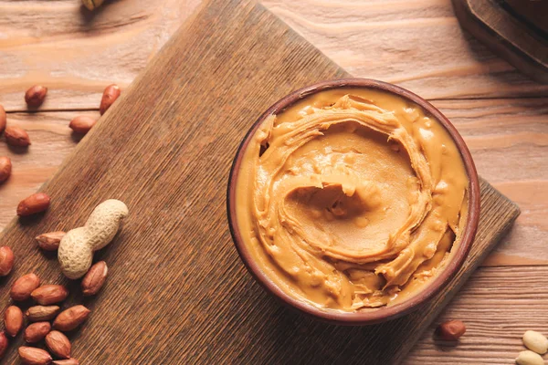 Cuenco con sabrosa mantequilla de maní en la mesa — Foto de Stock