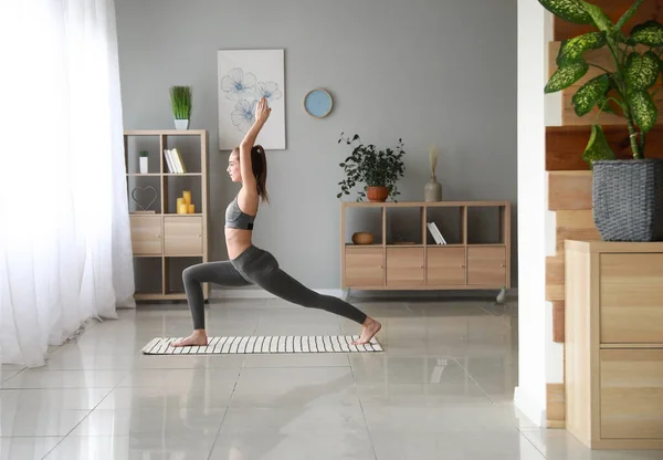 Beautiful young woman practicing yoga at home — Stock Photo, Image