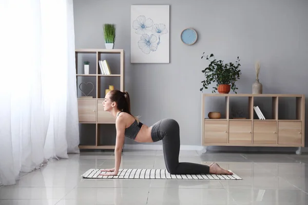 Beautiful young woman practicing yoga at home — Stock Photo, Image