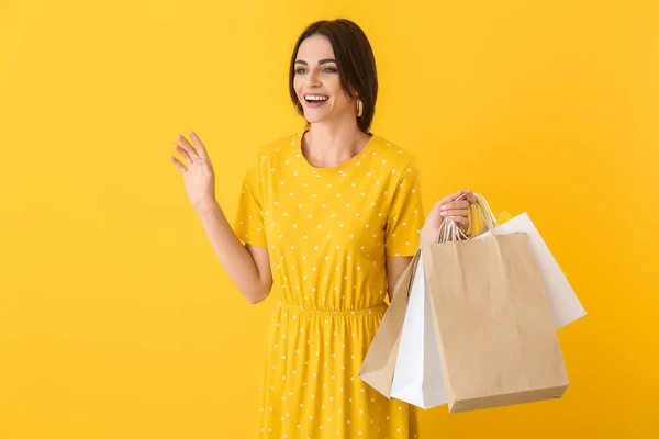 Krásná mladá žena s nákupními taškami na barevném pozadí — Stock fotografie