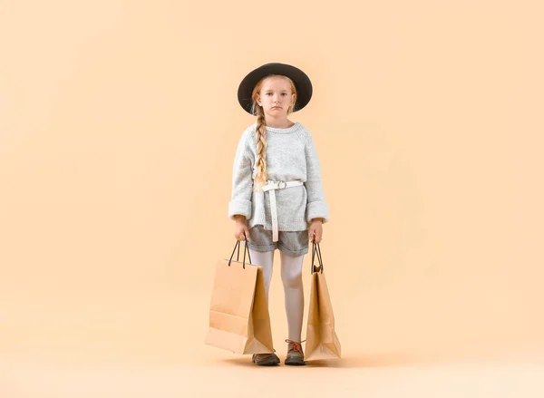 Roztomilé holčička v podzimním oblečení a s nákupními taškami na světlém pozadí — Stock fotografie