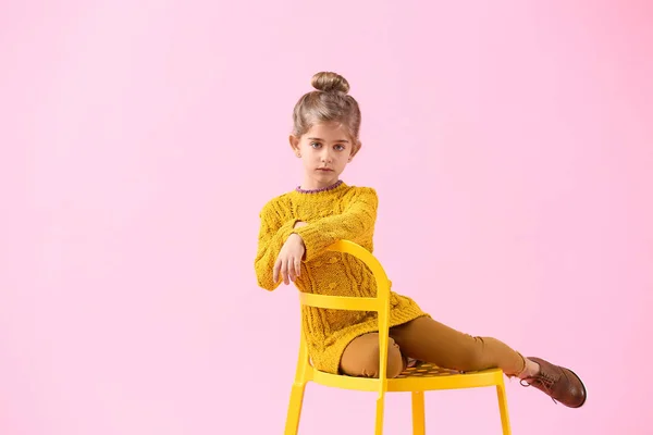 Linda niña en ropa de otoño sentada sobre fondo de color — Foto de Stock