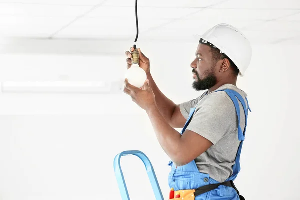 African-American electrician performing wiring in room — Stock Photo, Image