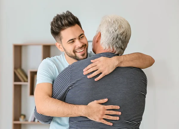 Jongeman en zijn vader knuffelen thuis — Stockfoto