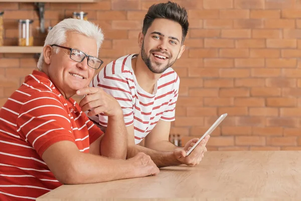 Jongeman en zijn vader met tablet computer in de keuken — Stockfoto