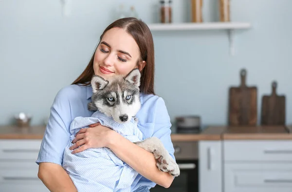 Cute woman with funny husky puppy in kitchen — Stock Photo, Image