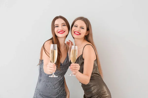 Beautiful young women with champagne on light background — Stock Photo, Image