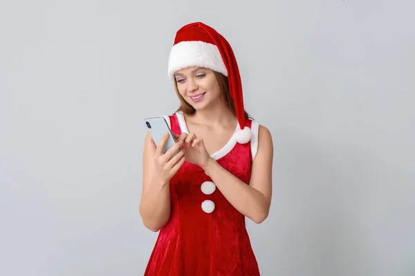 Giovane donna in costume da Babbo Natale su sfondo chiaro — Foto Stock