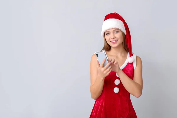 Giovane donna in costume da Babbo Natale su sfondo chiaro — Foto Stock