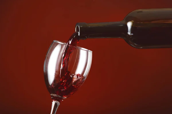 Pouring of wine into glass on color background — Stock Photo, Image