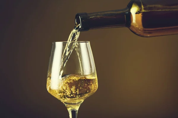Наливание вина в бокал на цветном фоне — стоковое фото