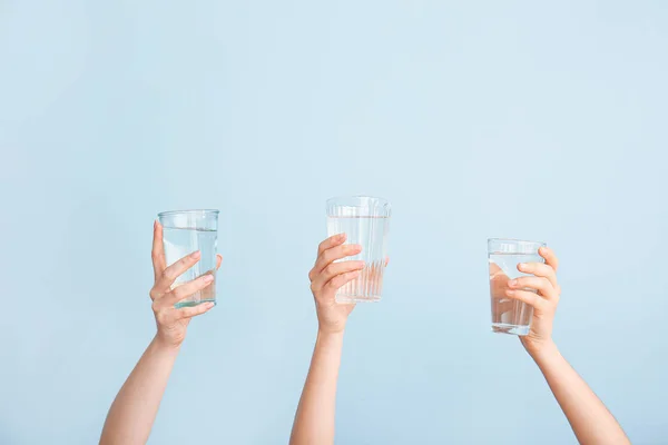 Weibliche Hände mit Wassergläsern auf farbigem Hintergrund — Stockfoto