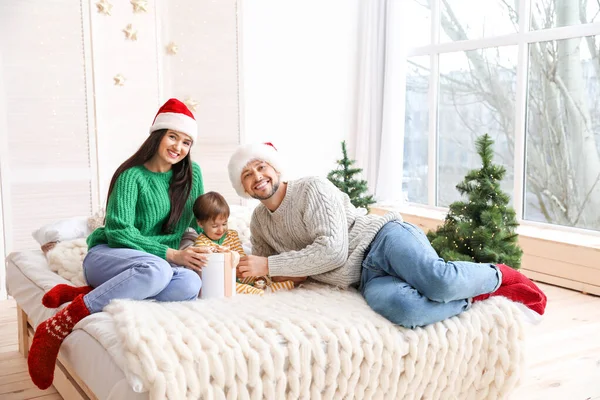 Familia feliz con regalo de Navidad en el dormitorio —  Fotos de Stock