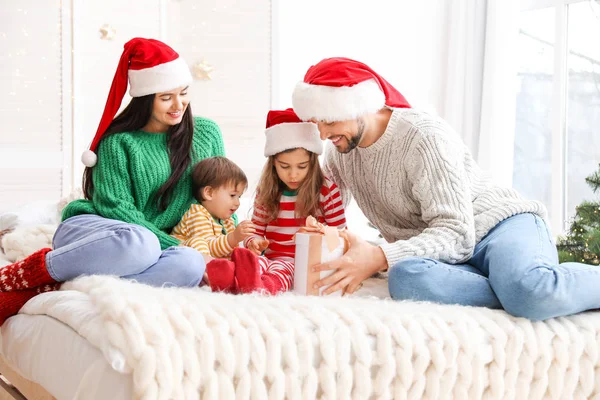 Familia feliz con regalo de Navidad en el dormitorio — Foto de Stock
