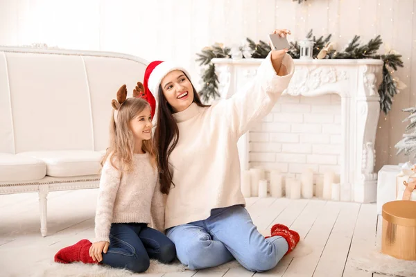 Mãe feliz com a filhinha tomando selfie na véspera de Natal em casa — Fotografia de Stock