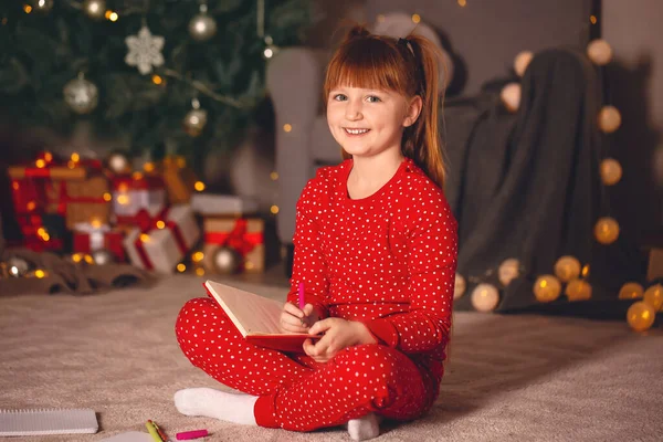 घरी ख्रिसमस संध्याकाळी सांता क्लॉजला सुंदर लहान मुलगी लेखन पत्र — स्टॉक फोटो, इमेज