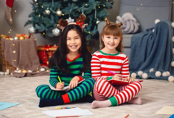 Niñas lindas escribiendo carta a Santa Claus en Nochebuena en casa — Foto de Stock