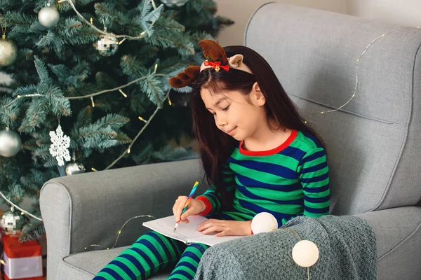 Cute little girl writing letter to Santa Claus on Christmas eve at home — Stock Photo, Image