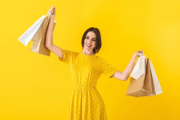 Красивая молодая женщина с пакетами покупок на цветном фоне — стоковое фото