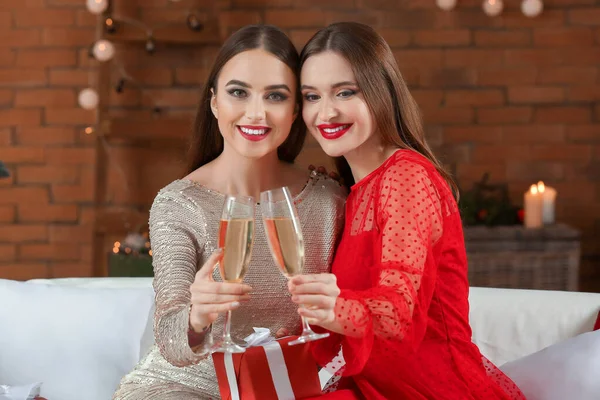 Beautiful young women with champagne celebrating Christmas at home — Stock Photo, Image