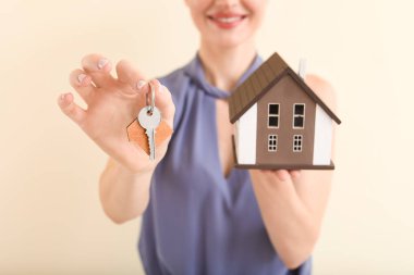 Arka planda anahtar ve model ev sahibi kadın emlakçı, yakın plan.