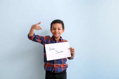 Beyaz arka planda Noel Baba 'ya mektup yazan tatlı Afro-Amerikalı çocuk.