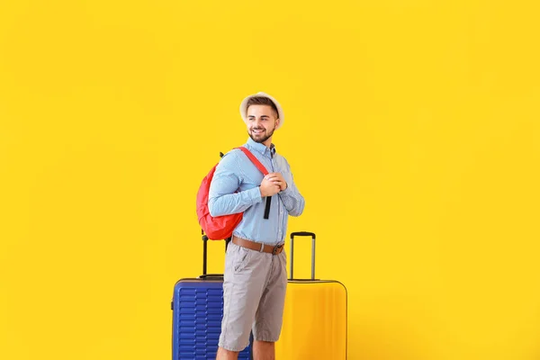 Young male tourist with luggage on color background — Stock Photo, Image