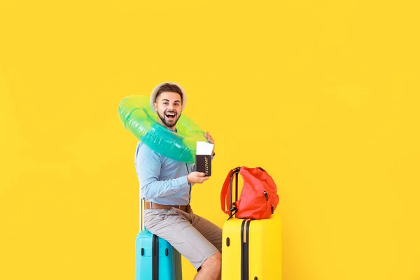 Young male tourist with luggage on color background — Stock Photo, Image