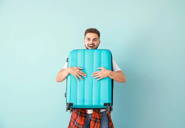 Young male tourist with luggage on color background — Stock Photo, Image