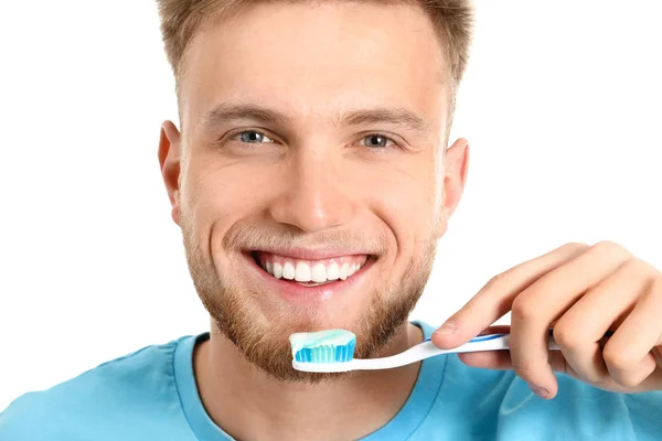 Young man brushing teeth on white background — Stock Photo, Image