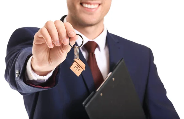 Male real estate agent with key on white background, closeup — Stock Photo, Image