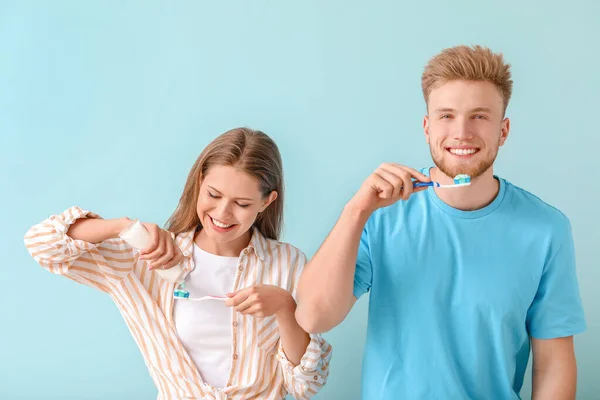 Young couple brushing teeth on color background — Stock Photo, Image