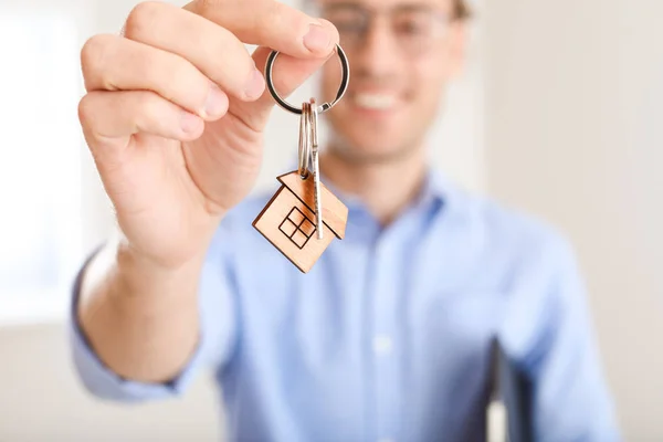 Male real estate agent with key indoors, closeup
