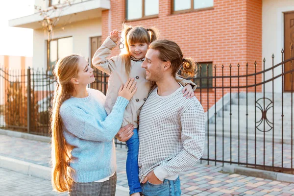 Família jovem com chave perto de sua nova casa — Fotografia de Stock